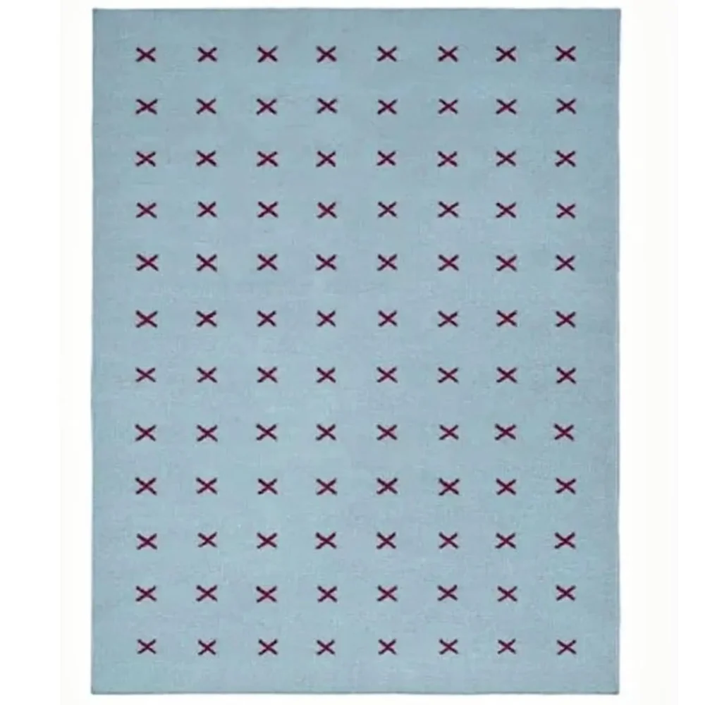 Scandinavian handwoven flatweave wool rug with a minimalist burgundy cross geometric pattern on a light blue background, handmade Nordic area rug for modern living room and bedroom.